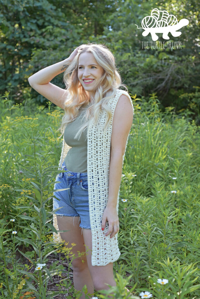 Woman wearing a medium length crochet vest.