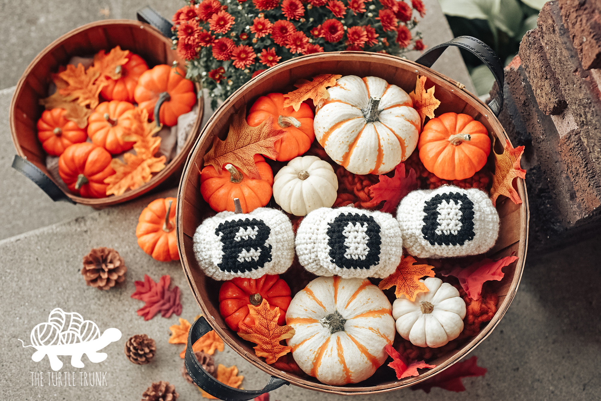 Photo shows 3 crochet pumpkins that say "BOO" sitting in a basket surrounded by real pumpkins. Crochet pattern is the BOO Pumpkin pattern by The Turtle Trunk.