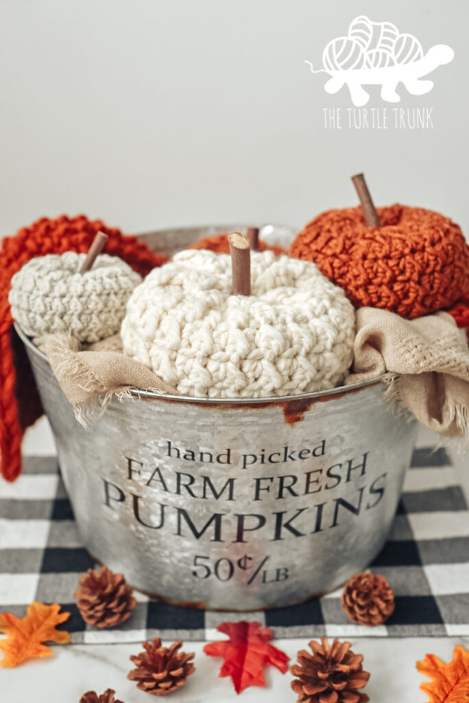 3 crochet pumpkins in a tin container.