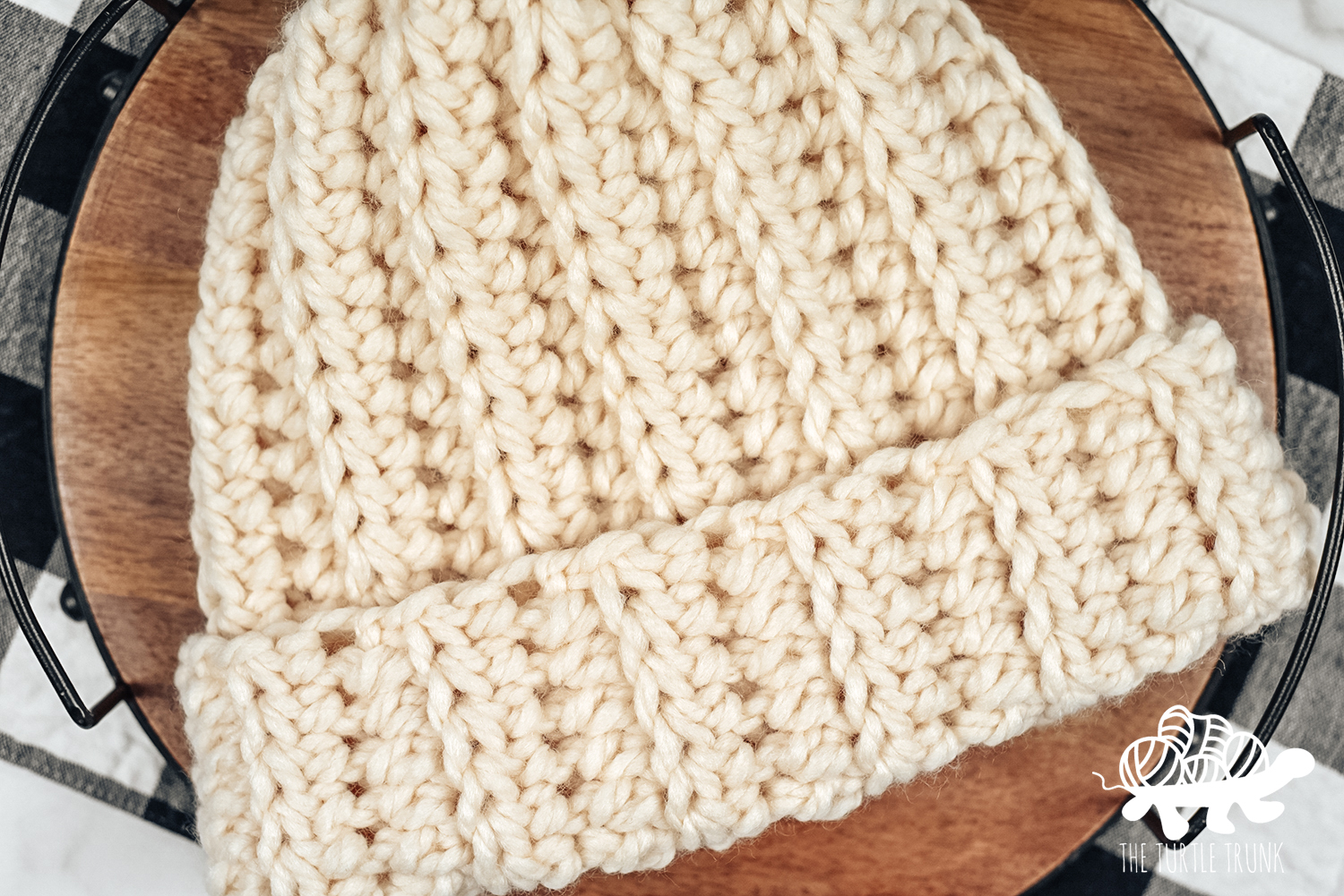 Close up shot of a white, crochet beanie that features a ribbed texture and fold over brim. Crochet pattern is the Easy Breezy Super Chunky Beanie by The Turtle Trunk.