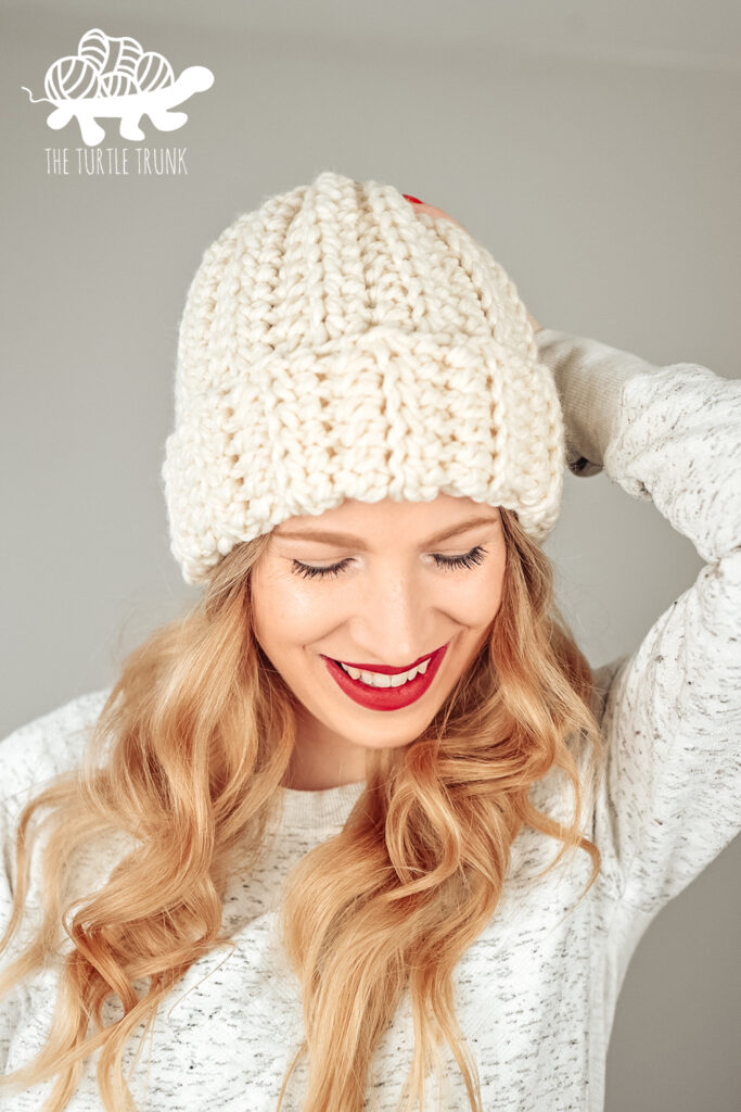 Woman wearing a white crochet beanie that features a ribbed texture and fold over brim. Easy Breezy Super Chunky Beanie by The Turtle Trunk.