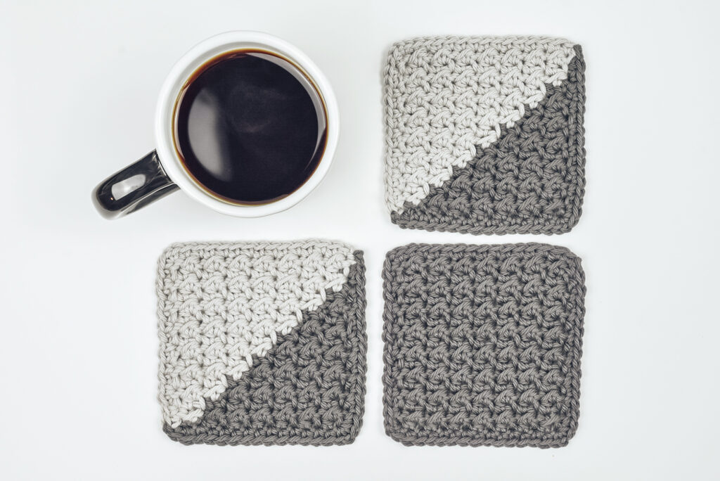 Photo shows light and dark grey, crochet coasters.