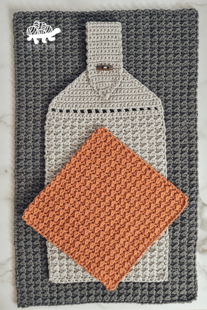 Photo shows a crochet dish cloth, dish towel, and hanging towel, Crochet pattern is the Farmhouse Dish Set by The Turtle Trunk.