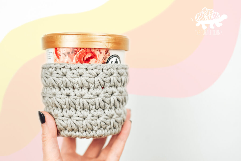 Hand holding a crochet, all star ice cream pint cozy on an ice cream pint. Crochet pattern by The Turtle Trunk.