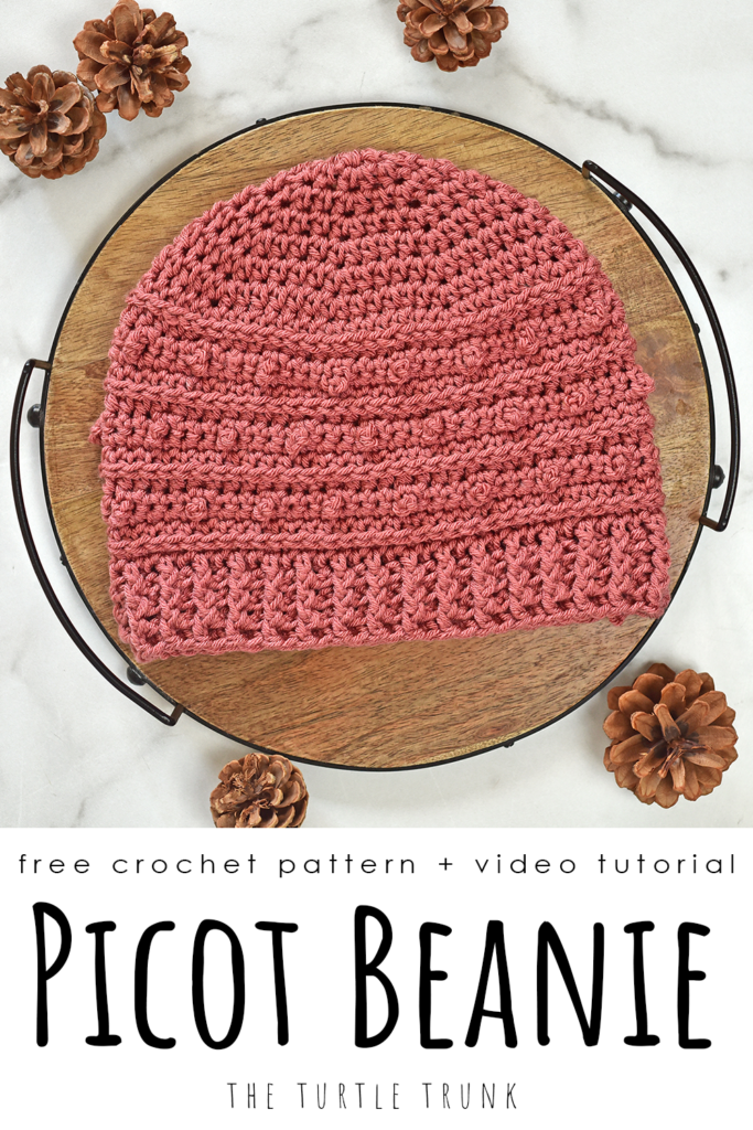 Pinterest pin for the Picot Beanie crochet pattern by The Turtle Trunk. The photo shows a pink, crochet hat laying on a white surface.