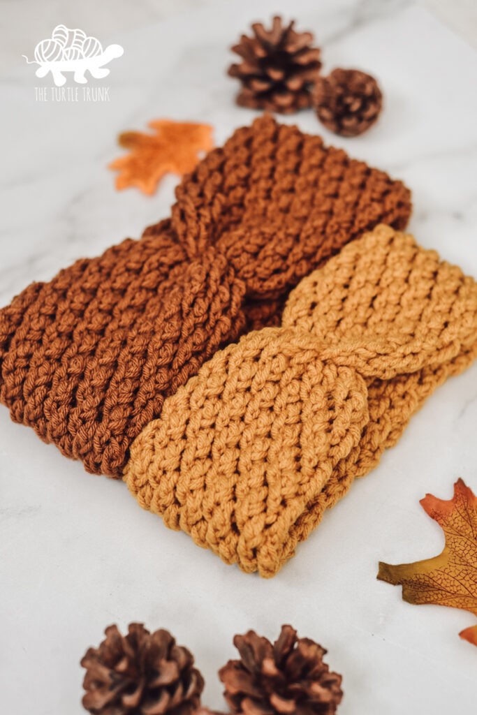 Photo shows 2 crochet headbands laying on a white surface. Crochet pattern is the Country Cottage Headband by The Turtle Trunk.