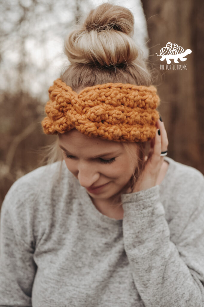 Woman outside wearing a yellow crochet ear warmer. Crochet pattern is the Cloud Nine Headband by The Turtle Trunk.