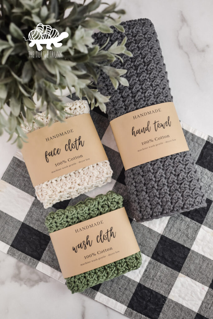 3 crochet cloths with paper labels wrapped around them. Crochet pattern is the Farmhouse Dish Set by The Turtle Trunk.