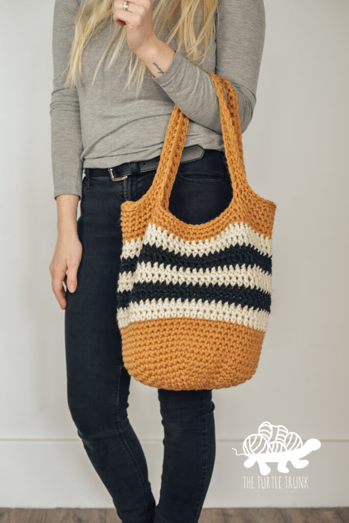 Women holding a yellow, black, and white crochet tote bag.