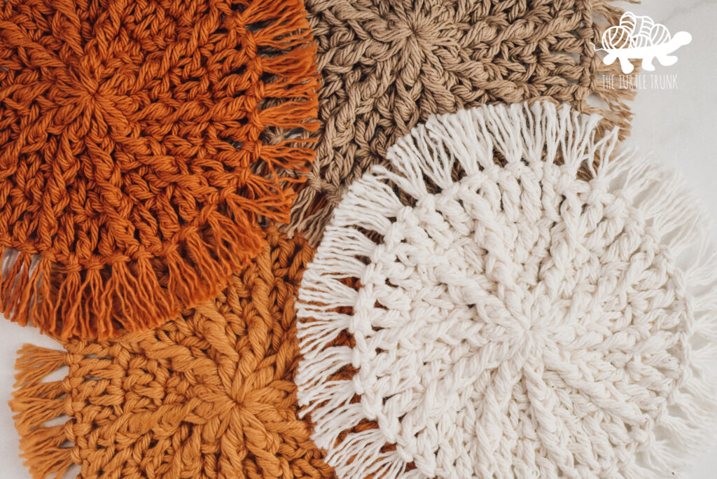 Closeup shot of 4 crochet coasters laying on a white surface. Hello Sunshine Coaster crochet pattern by The Turtle Trunk.