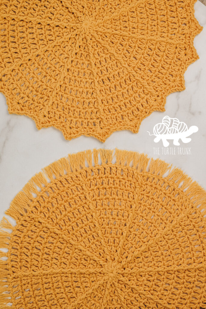 Photo shows 2, yellow crochet placemats laying on a white surface. Crochet pattern is the Hello Sunshine Placemat by The Turtle Trunk.