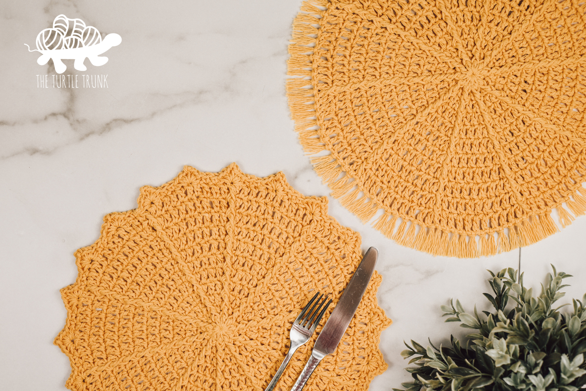 Photo shows 2 yellow, crochet placemats laying on a white surface.