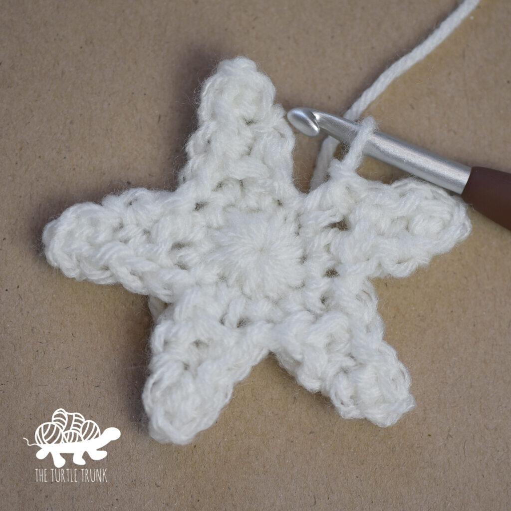 Progress photo of a white, crochet star.