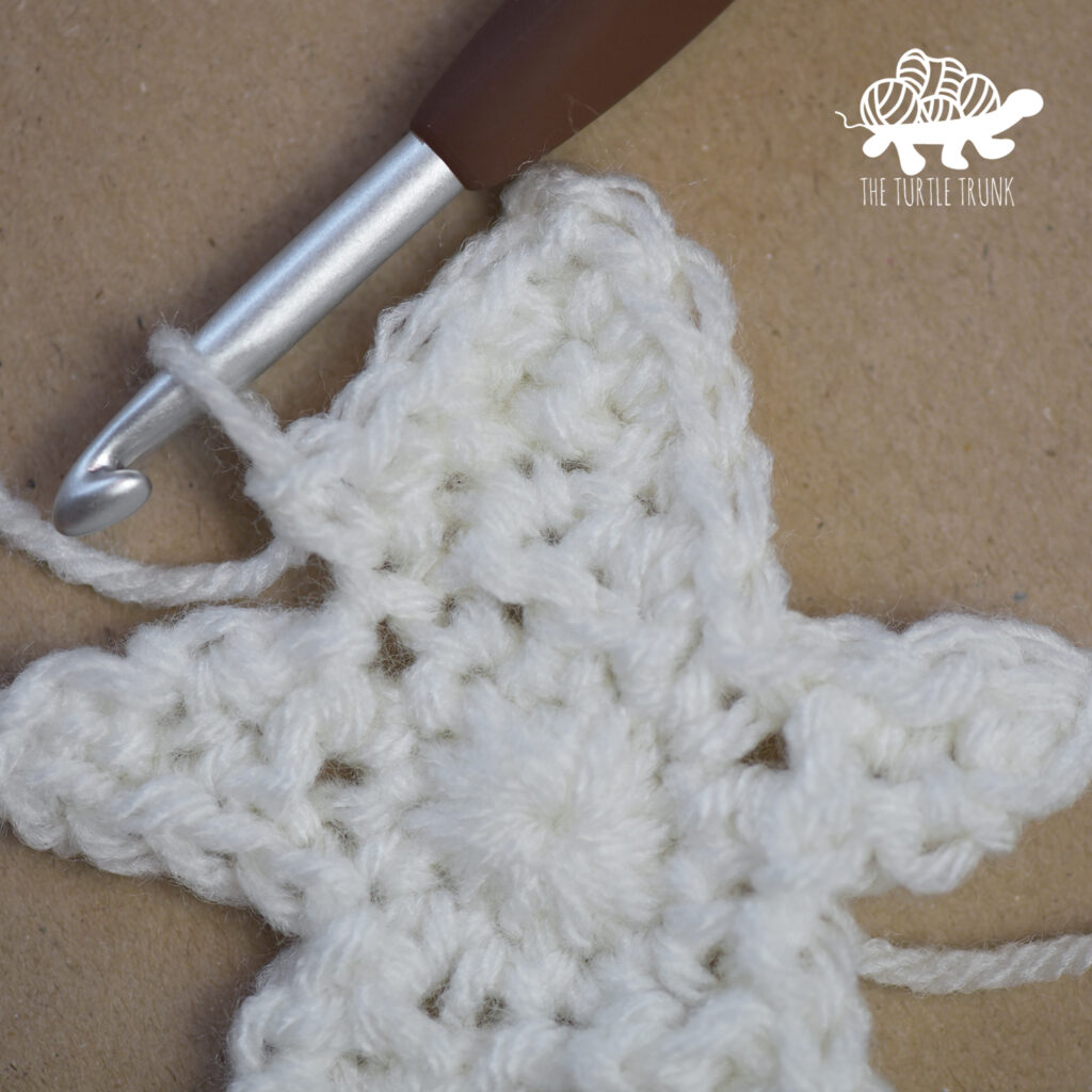 Progress photo of a white, crochet star.