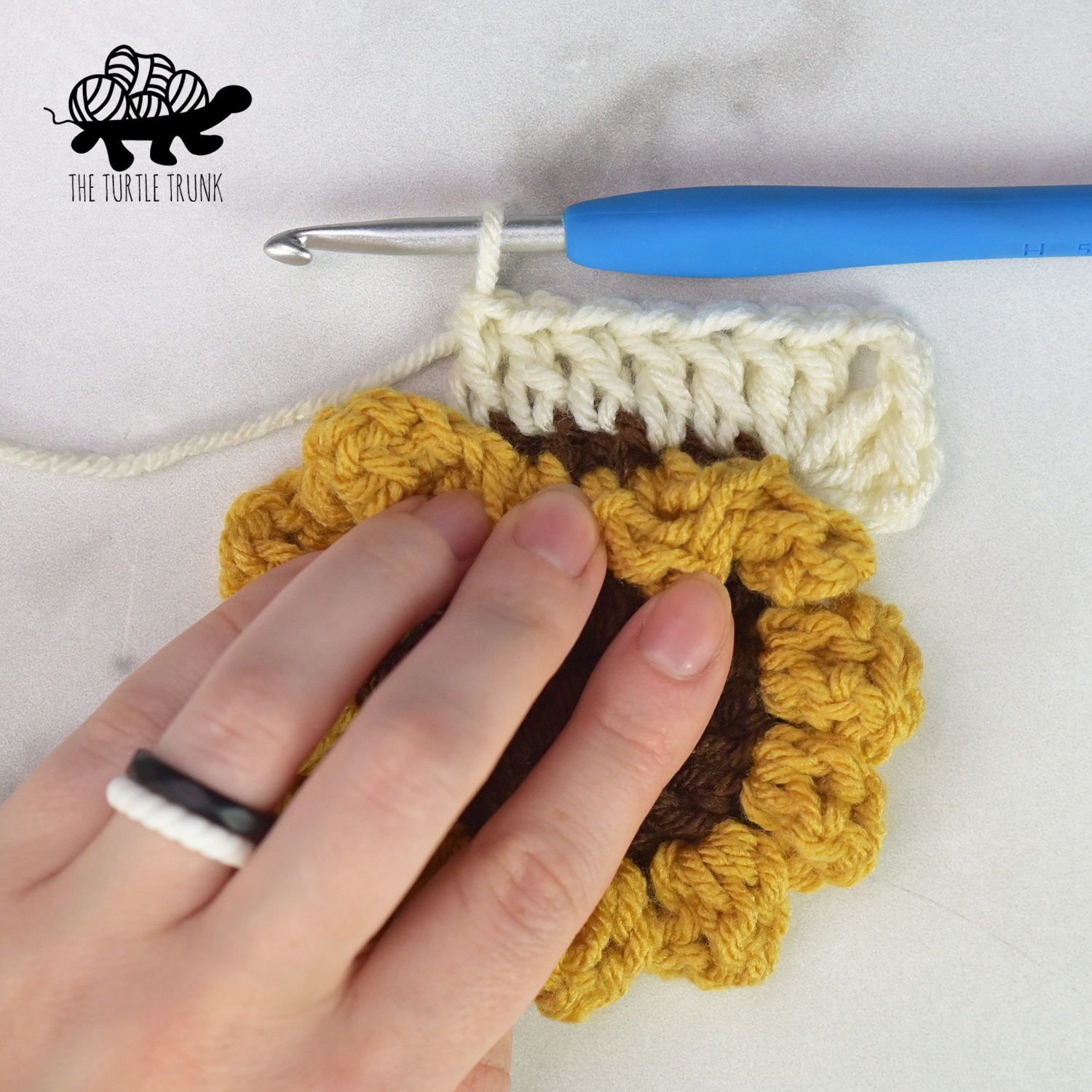 Working round 4 of the sunflower square. Shows a crochet sunflower with one corner and one side of a square around it.