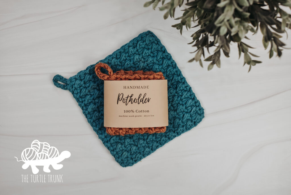 Photo shows a green, crochet potholder laying on a white surface.