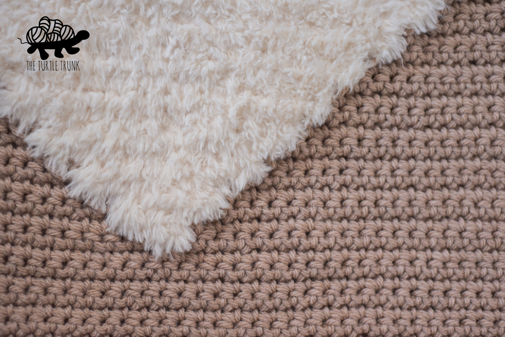 Photo shows a close up shot of a blush pink crochet blanket with a white faux fur heart  on it. The crochet pattern is the Love to Cuddle Blanket by The Turtle Trunk.