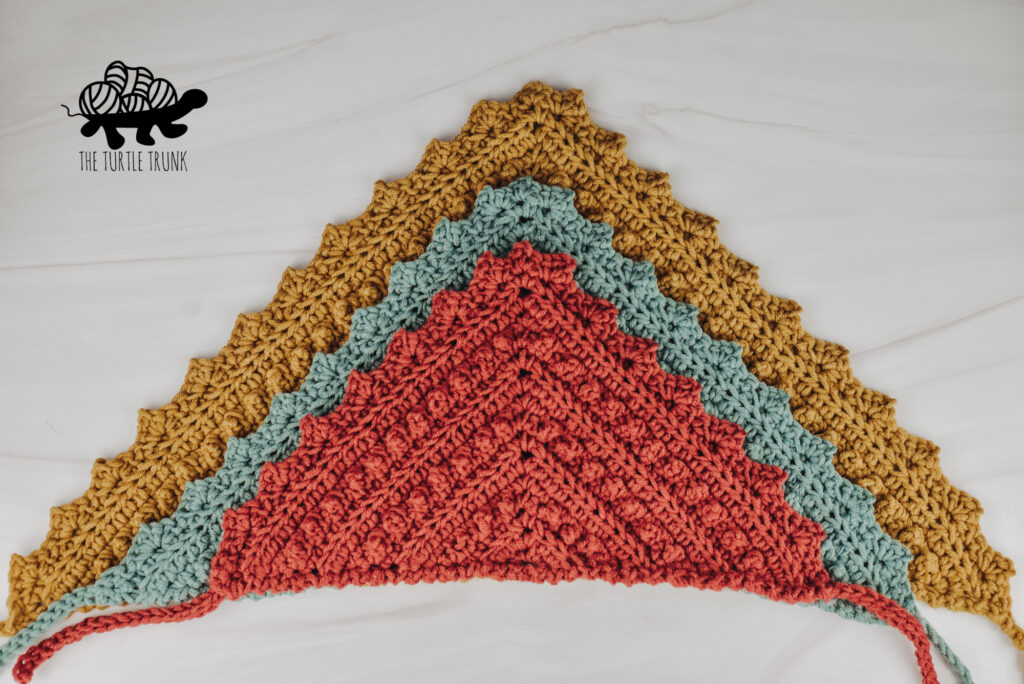 Photo shows 3 crochet bandanas laying on top of each other on a white surface. Crochet pattern is the Picot Bandana by The Turtle Trunk.