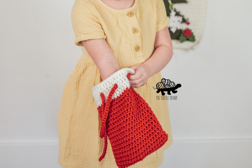 Little girl reaching into a crochet pouch and gift bag.