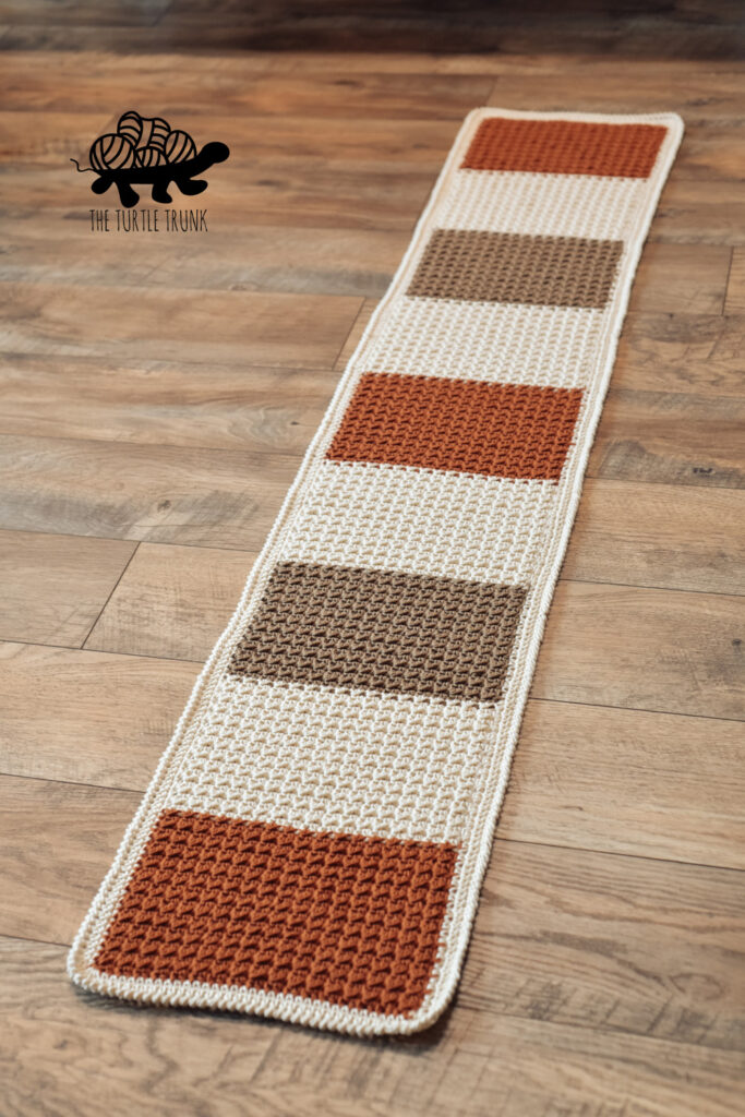 Photo shows a striped, crochet table runner.