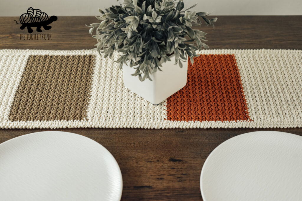 Photo shows a crochet table runner on a wooden table.