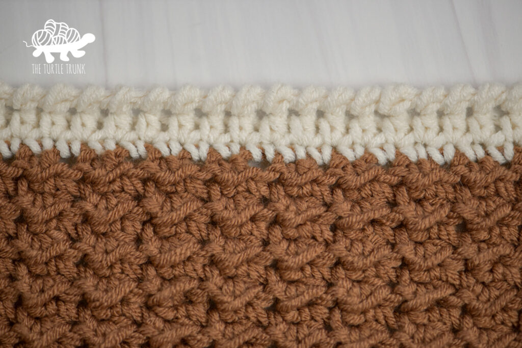 Close up of a crochet blanket with a crab stitch border.