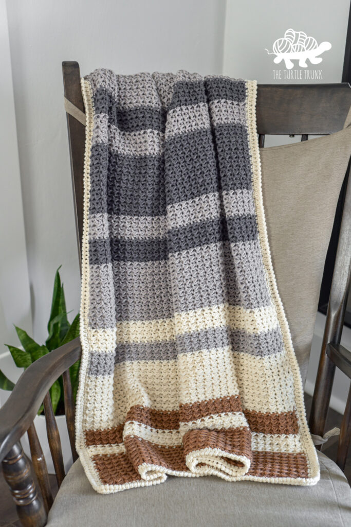 A crochet blanket on a rocking chair.