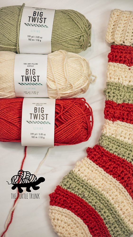 3 skeins of red, white, and green yarn and a crochet Christmas stocking.