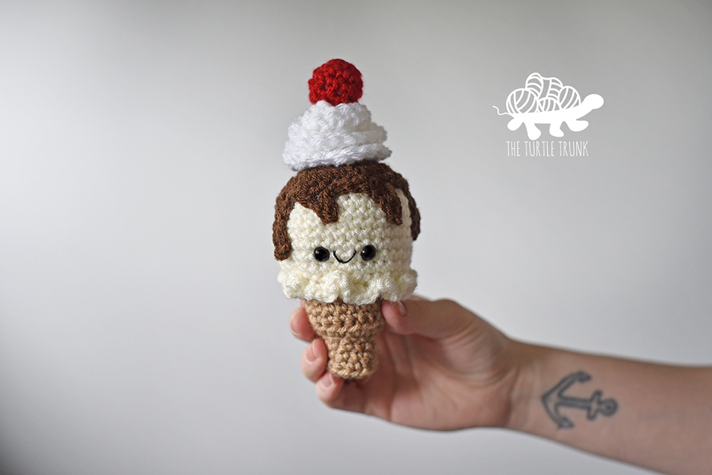 Crochet amigurumi ice cream cone with crochet chocolate sauce, whipped cream, and cherry on top.