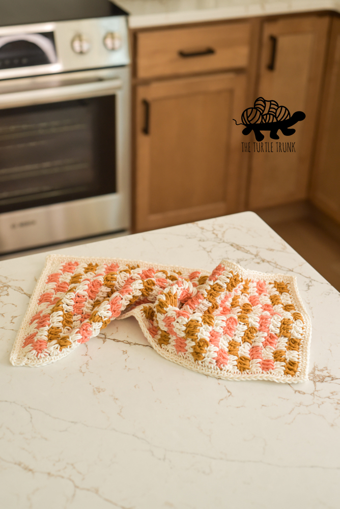 A crochet checkered dish towel lay on a countertop.
