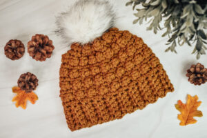 A orange-brown, crochet beanie on a white background.
