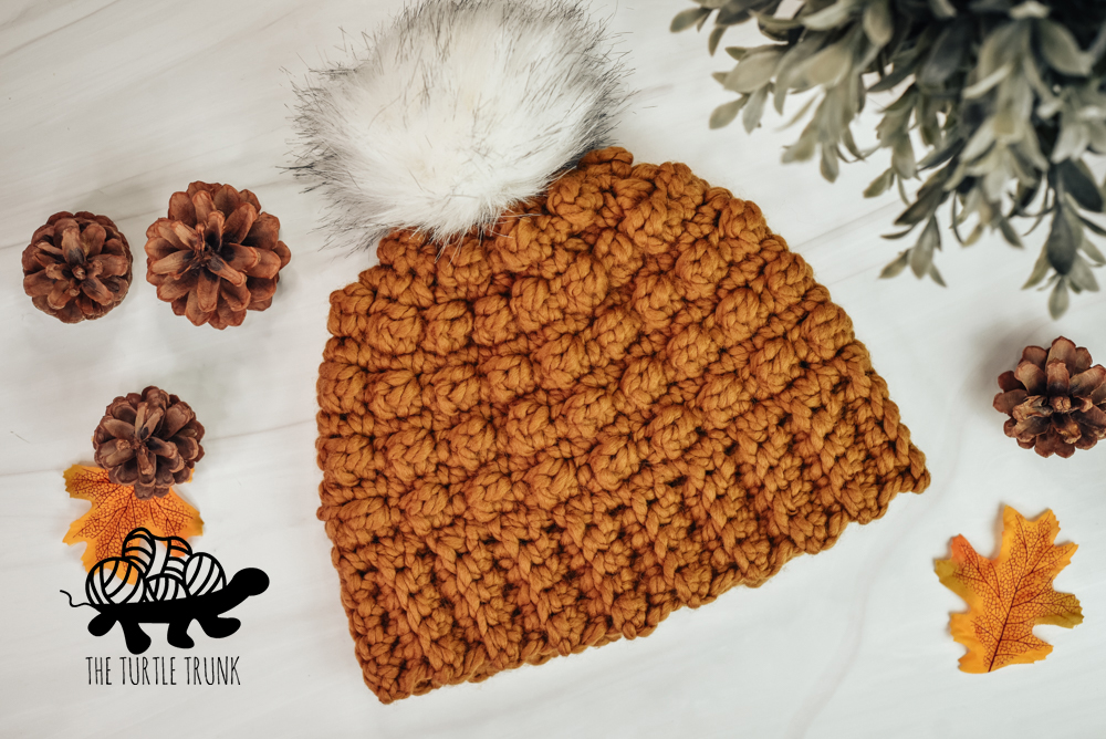 A orange-brown, crochet beanie on a white background.