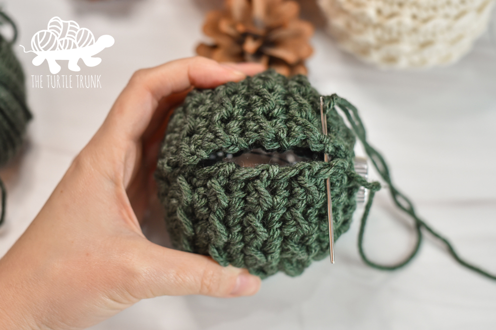 Women sewing up a crochet ornament.