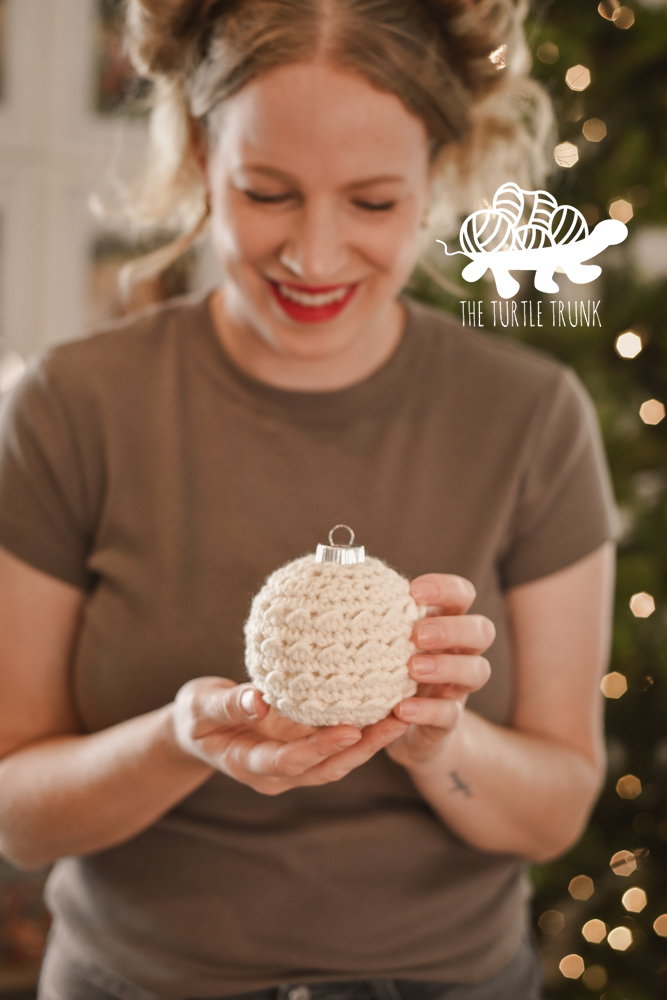 Woman holding a crochet ornament.