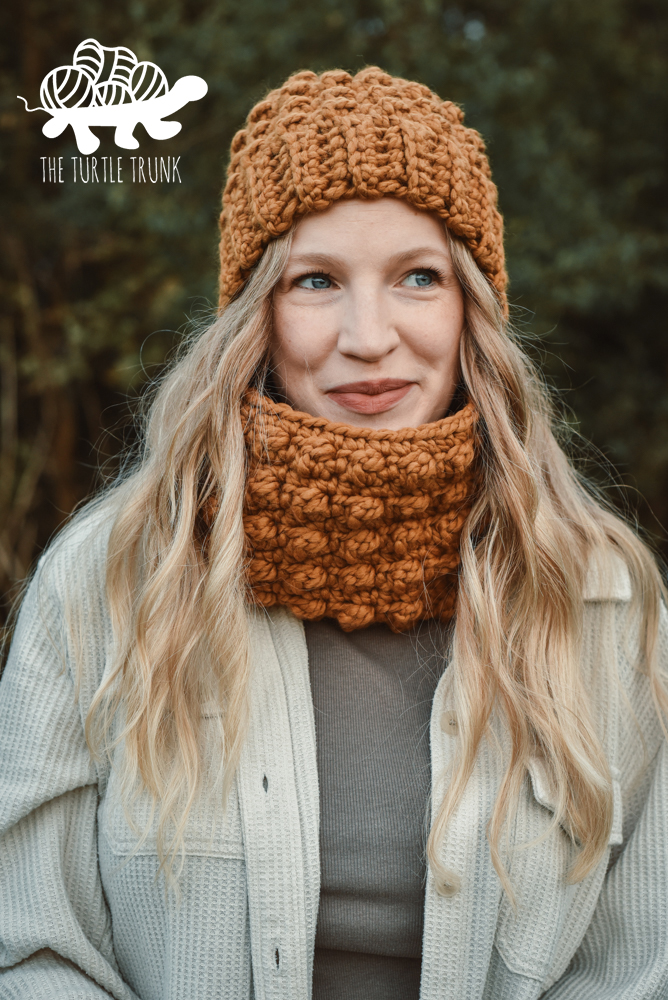 Woman wearing a matching crochet berry stitch beanie and cowl.