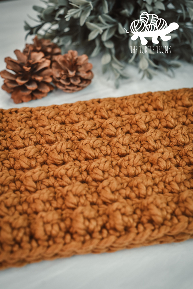 A closeup of a crochet cowl featuring the berry stitch.