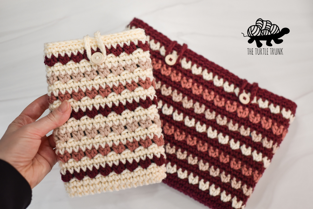 Hand holding a crochet e-reader sleeve.