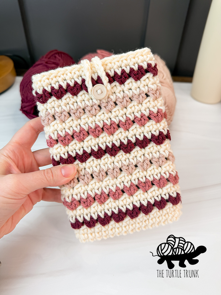 A hand holding a crochet e-reader sleeve.