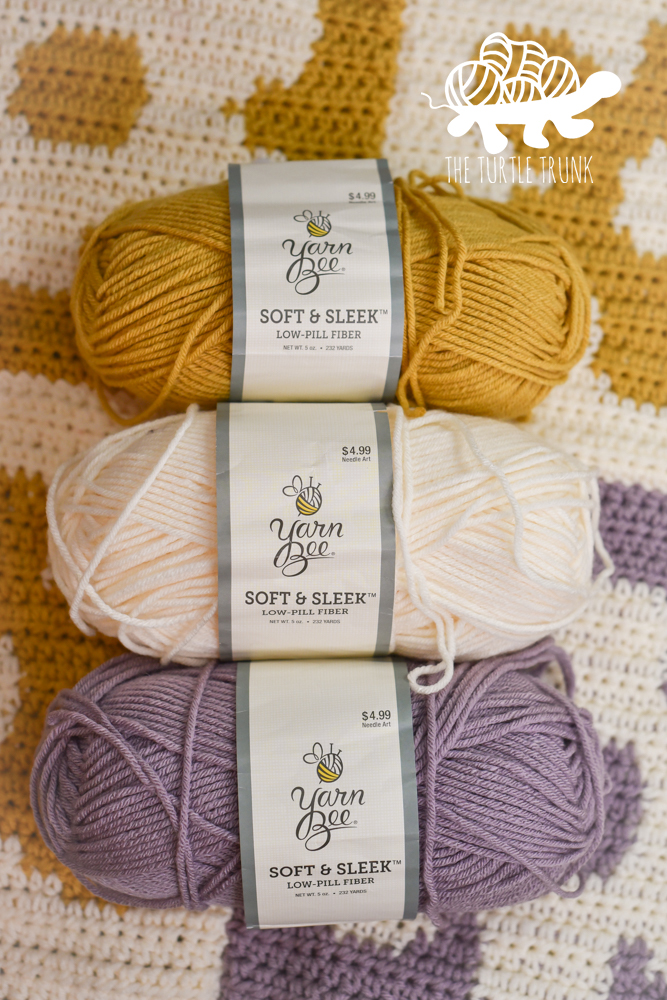 Yarn Bee Soft and Sleek yarn in the colors mustard, ivory, and purple haze for the Checkered Flower Blanket crochet pattern by The Turtle Trunk.