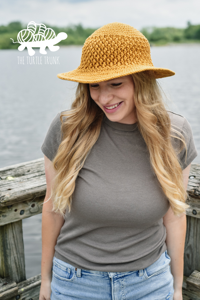 Woman wearing a yellow, crochet sun hat with a wide brim. Crochet pattern is the Country Cottage Sun Hat by The Turtle Trunk.