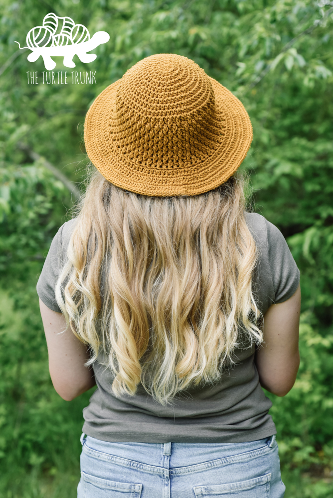 Woman wearing a yellow, crochet sun hat with a wide brim. Crochet pattern is the Country Cottage Sun Hat by The Turtle Trunk.